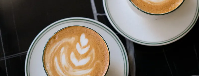 Two cappuccinos on a marble cafe table, seen from above
